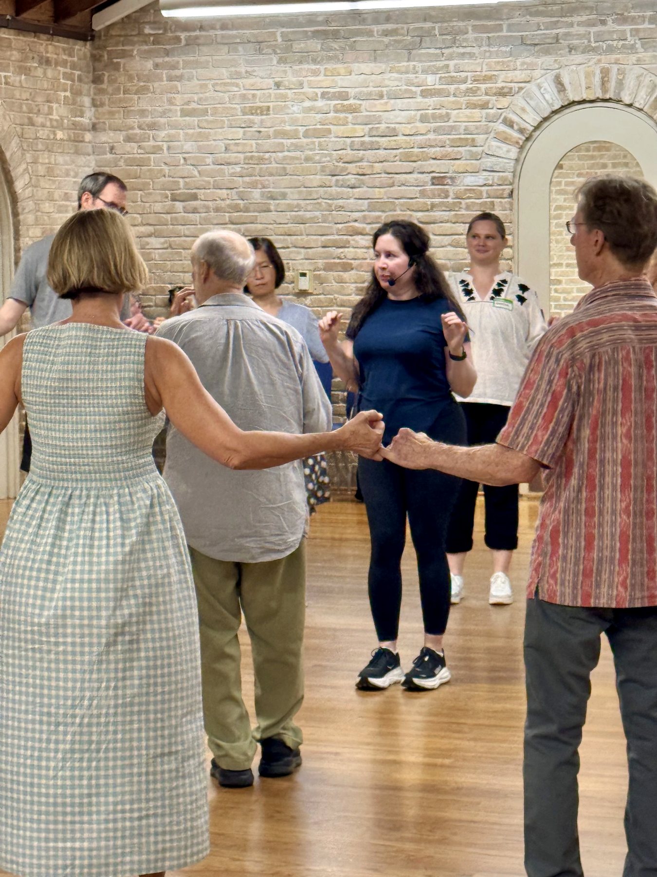 Sonique leading a circle of folk dancers through the steps