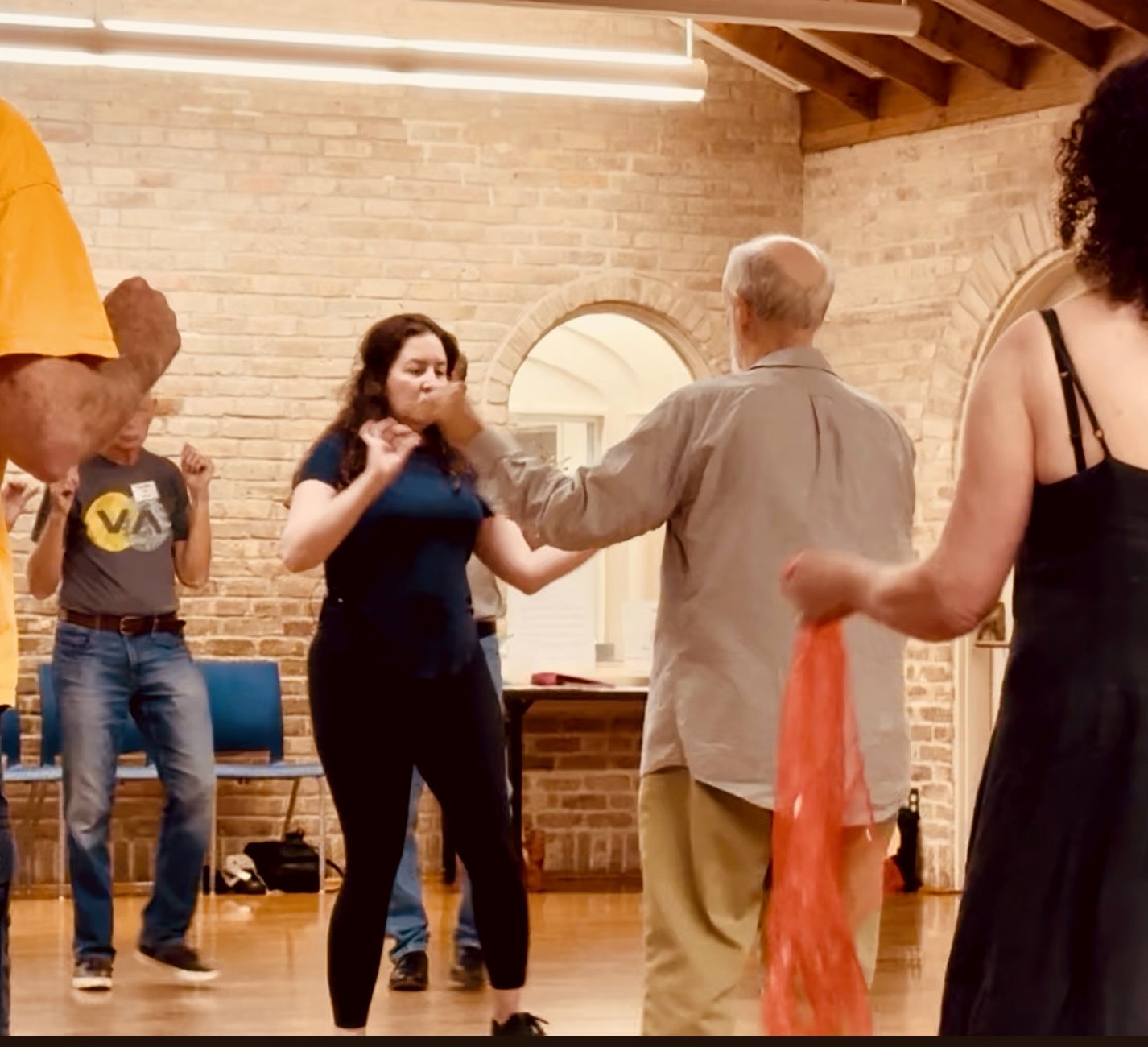 Dancers mid-step, one with a red scarf, on the Hancock Recreation Center floor
